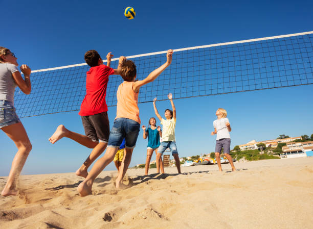 ragazzi e ragazze che giocano a pallavolo sulla spiaggia - volleyball net leisure activity beach foto e immagini stock