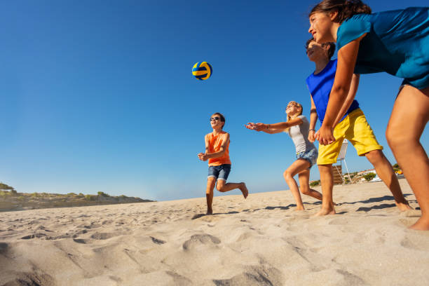 enfants jouer au volleyball de plage pendant les vacances - beach volleying ball playing photos et images de collection