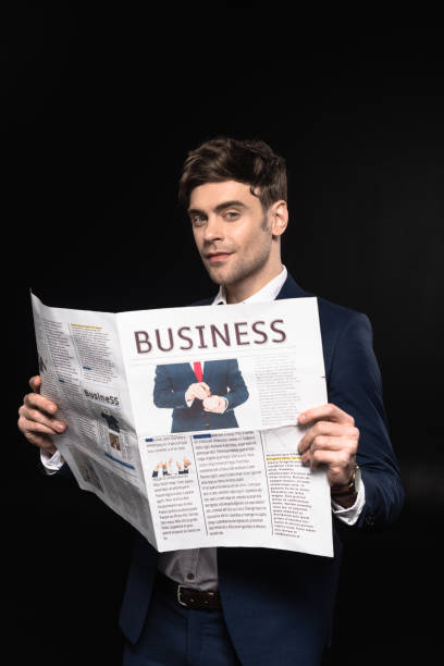 istock attractive young businessman with newspaper looking at camera isolated on black 1068405088