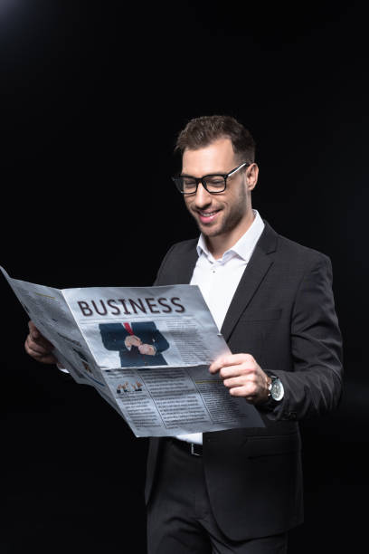 istock handsome young businessman reading newspaper isolated on black 1068405164