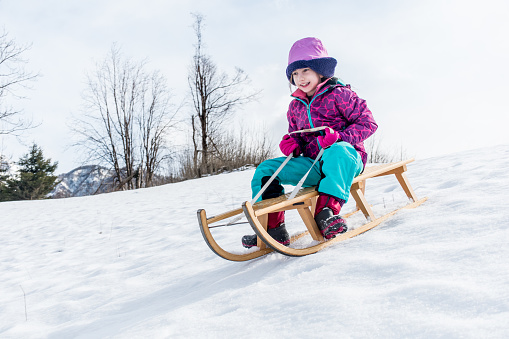 Smiling Young Girl Riding on Sled.