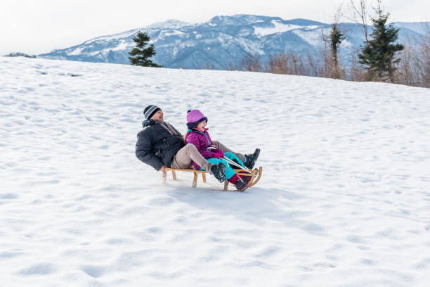 istock Daughter and Father Enjoying Riding on Sled Together 1068405546