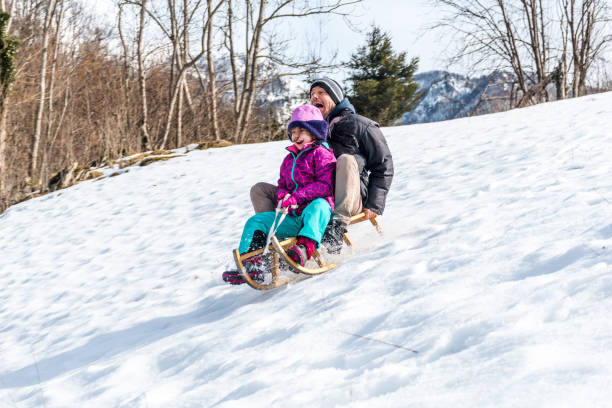 istock Daughter and Father Enjoying Riding on Sled Together 1068405566