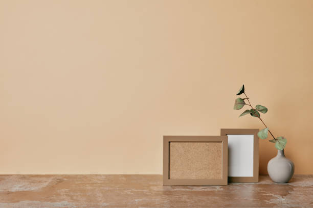 istock Two photo frames and vase with flower on table on beige background 1068407508