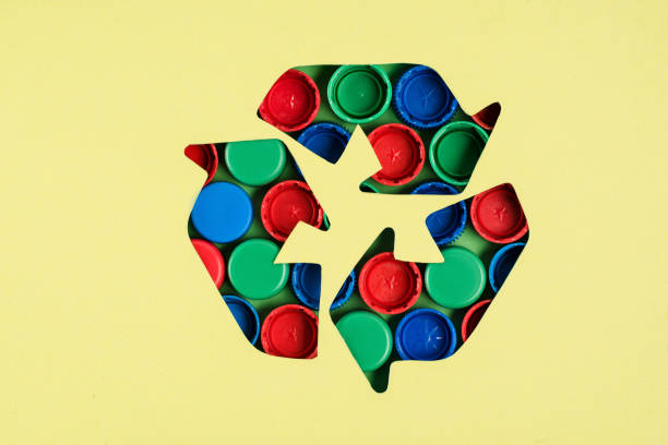 istock Top view of recycle sign with bottle caps pattern on yellow background 1068411932