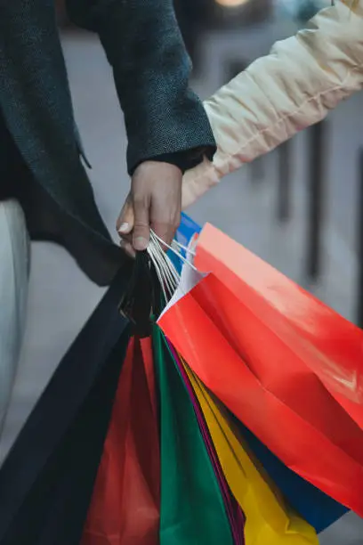 Photo of Close-up of hands holding shopping bags.