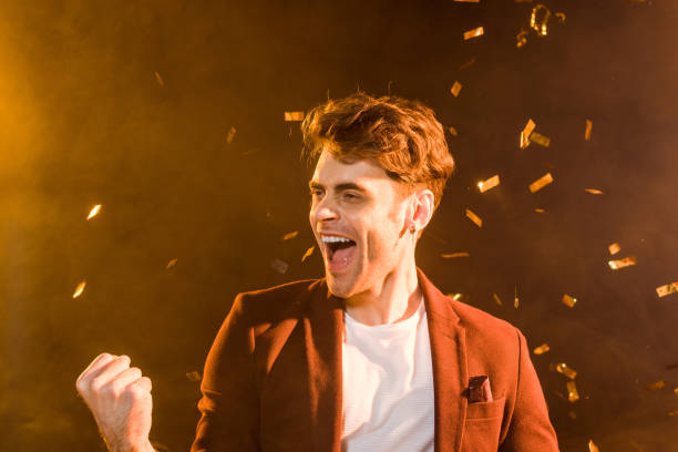 istock celebrating young man under falling confetti on black 1068416858