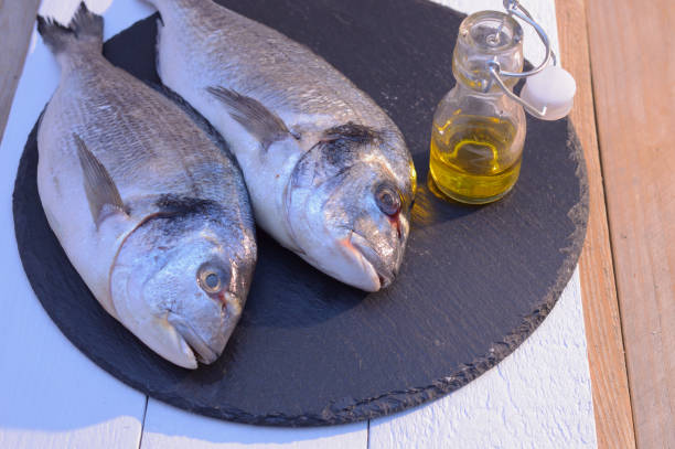 istock dorado fish on a black plate with olive oil bottle 1068420744