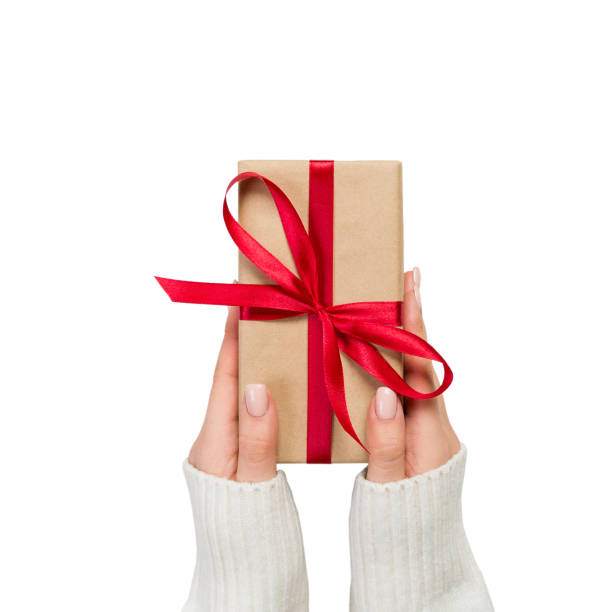 mains de femme tenant cadeau enveloppé et décoré avec l’arc rouge isolé sur blanc - color image copy space high angle view isolated photos et images de collection