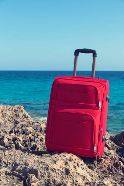 istock Red suitcase in a rocky coast. Selective focus 1068423280
