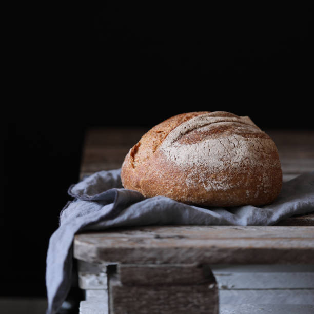 istock Bread at wood board with napkin on dark background 1068439438