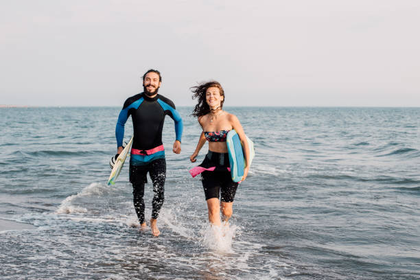 istock Surfing couple running in the water 1068440296