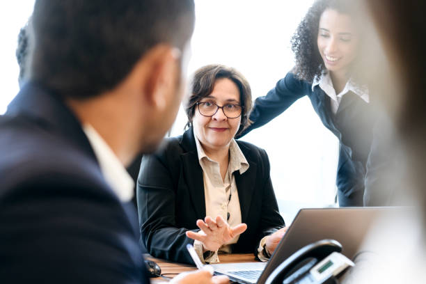 istock Mature businesswoman using laptop and explaining 1068445282