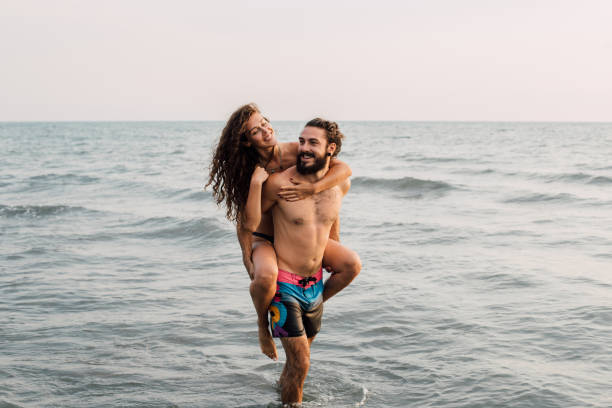 istock Man holding girlfriend on his back at the beach 1068448894