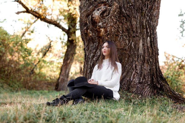 istock beautiful woman in black hat sitting under big tree 1068461430