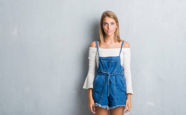 istock Beautiful young woman standing over grunge grey wall with serious expression on face. Simple and natural looking at the camera. 1068464592