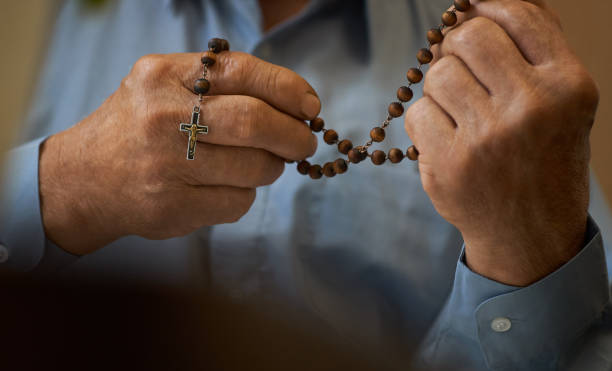 istock Praying hands of an old man holding rosary beads. 1068464672