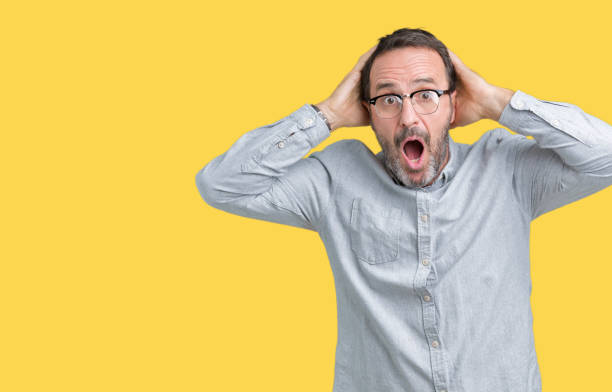 istock Handsome middle age elegant senior man wearing glasses over isolated background Crazy and scared with hands on head, afraid and surprised of shock with open mouth 1068470208