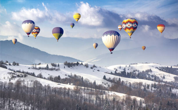 Multicolored hot air balloons on a mountain ridge covered snow
