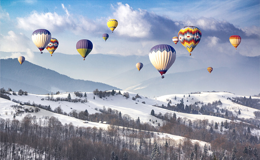 Multicolored hot air balloons on a mountain ridge covered snow