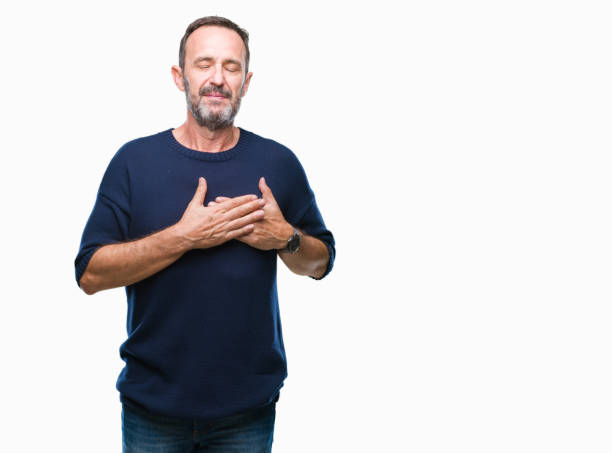 istock Middle age hoary senior man over isolated background smiling with hands on chest with closed eyes and grateful gesture on face. Health concept. 1068473590