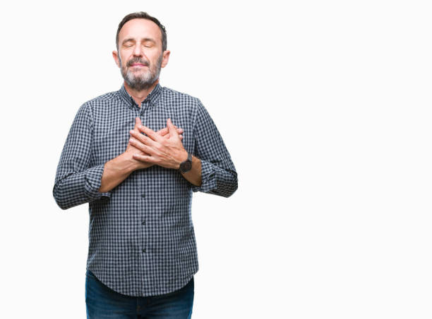 istock Middle age hoary senior man over isolated background smiling with hands on chest with closed eyes and grateful gesture on face. Health concept. 1068473702