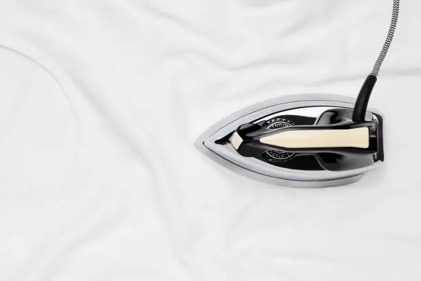Retro iron ironing a white wrinkled t-shirt. Top down view with copy space.