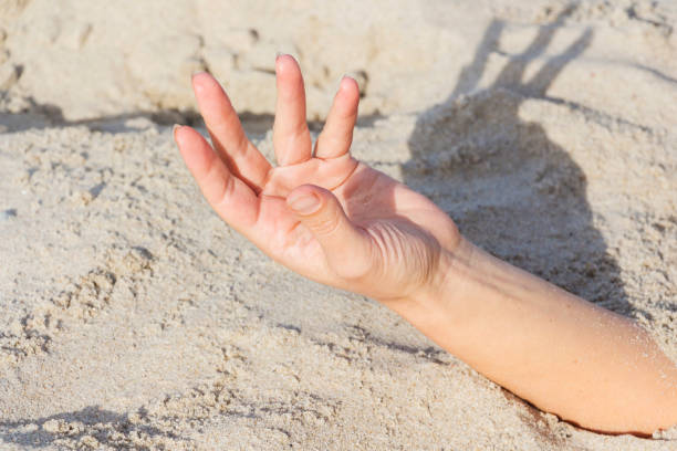 istock Hand closeup. Hands buried in sand on a beach. 1068484258