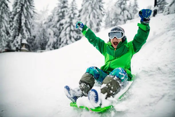 Little boy having extreme winter fun on sled. The boy is sledding down hill and yelling.
Nikon D850