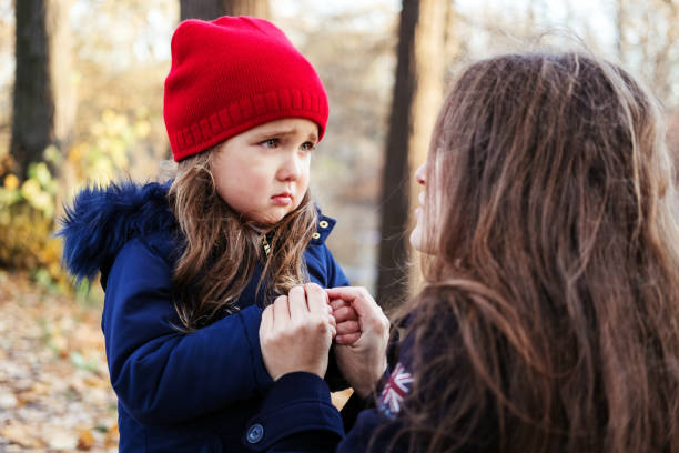 figlia spaventata che tiene le mani della madre nel parco autunnale. bambina esprime emozioni tristi, si lamenta dei propri problemi - women crying distraught thinking foto e immagini stock