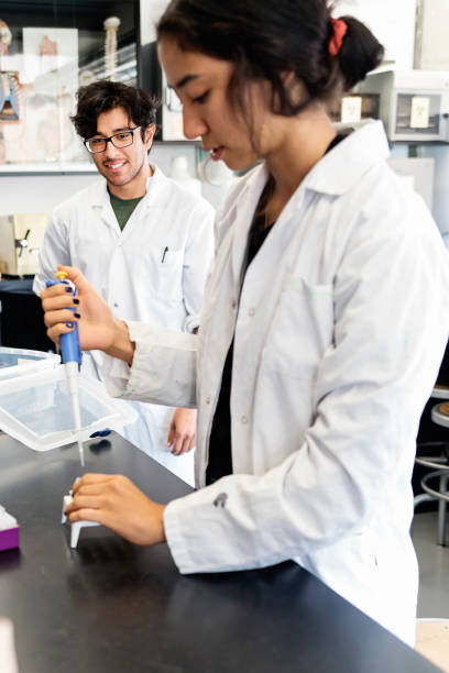 istock Multi-ethnic professor and student in college science laboratory. 1068510566