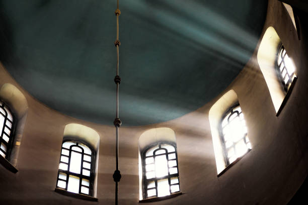 Sun rays make their way through the high vaulted arched window under dome in church temple Concept religion enlightenment light and dark
