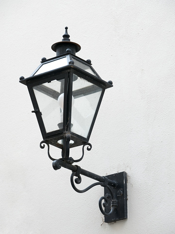 The street lamp is built into the wall of the building.