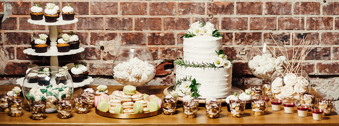 Delicious wedding reception candy bar and dessert table. Wedding catering, table with modern desserts and cupcakes.