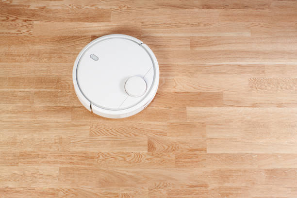 istock white Robotic vacuum cleaner runs on laminate floors. modern smart cleaning technology housekeeping. Flat lay top view. With your place for the text 1068560606