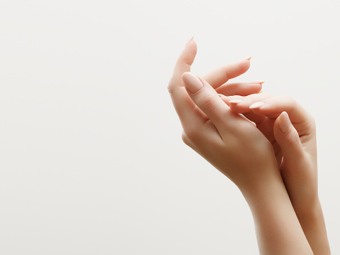 Cuidado de la piel de mano. Primer plano de manos de mujer hermosa con luz manicura en uñas. Crema para manos y tratamiento. photo