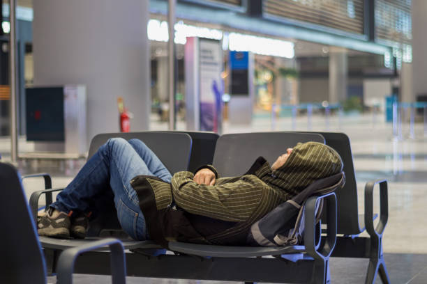 istock Young man sleeping while waiting the plane at airport passenger terminal 1068572958