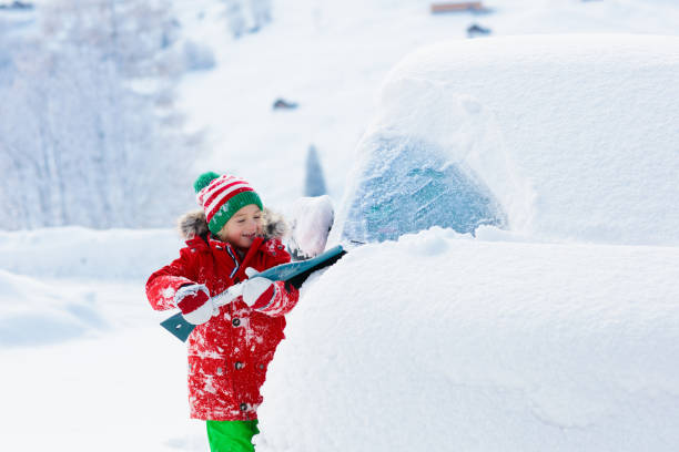 istock Child brushing off car. Kid with winter snow brush 1068581198
