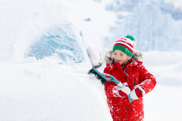 istock Child brushing off car. Kid with winter snow brush 1068583994