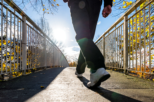 bright sunny morning view of man walking on pedestrian bridge in british autumn.