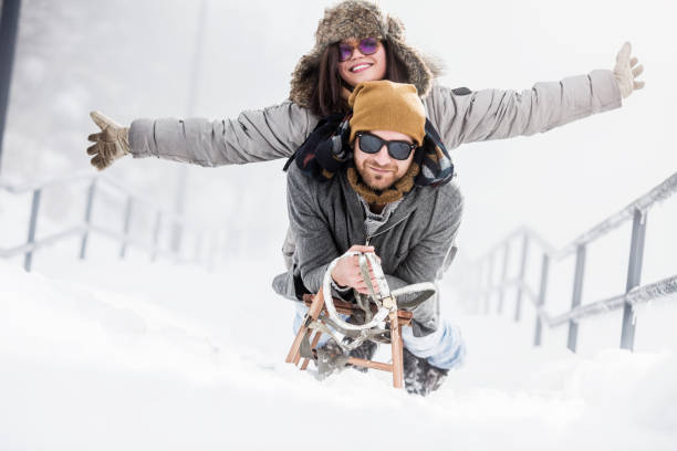 istock Beautiful couple with sled in snow 1068590252