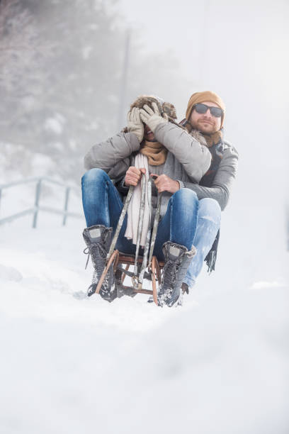 istock Beautiful couple with sled outdoors playing in snow 1068590286