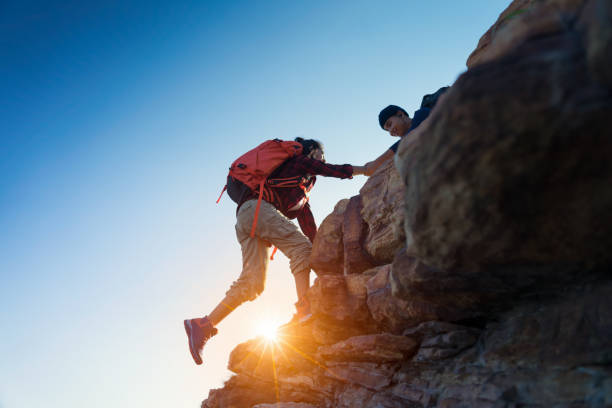 jeune couple asiatique, grimper sur la montagne - climbing adventure hiking assistance photos et images de collection