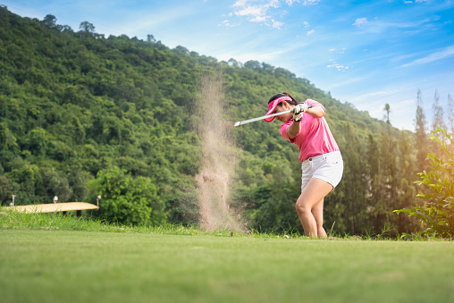 Young women player golf swing shot on course in morning sunrise