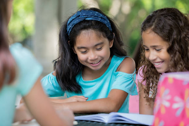 istock Study group of diverse elementary school girls reading book together 1068595608