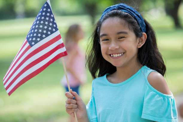 istock Elementary age Asian little girl smiles while holding American flag 1068601000