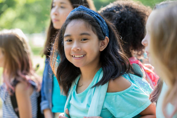 istock Asian elementary age little girl smiles while waiting outside school with classmates 1068605944