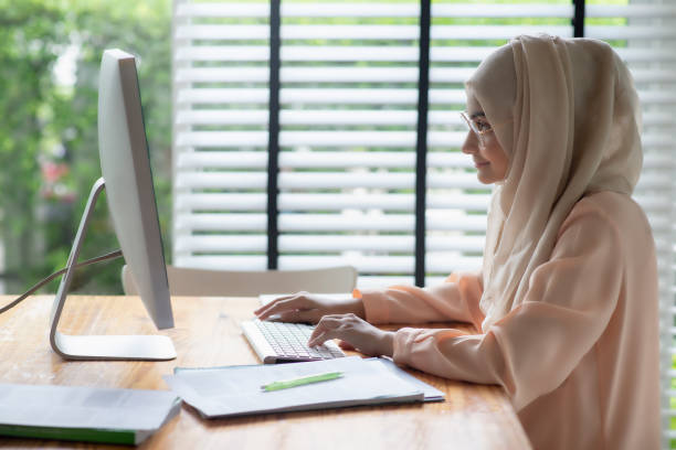 asiatische muslimische schüler arbeiten mit computer im zimmer. - religiöse kleidung stock-fotos und bilder