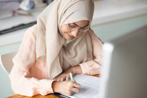 istock Young muslim student writing and working in traditional clothes. 1068609690