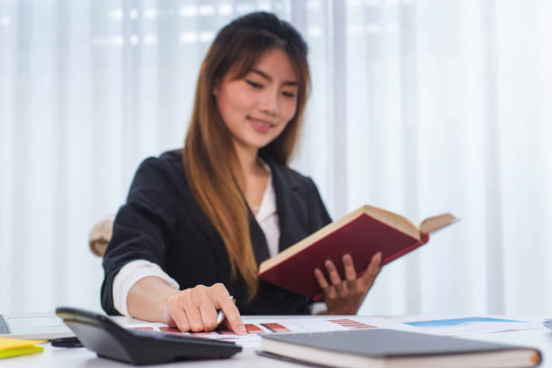 istock Business young women reading book at workplace in office. Knowledge and education concept 1068622924